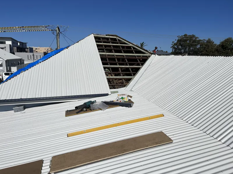 New white Colorbond roof sheets being installed over fresh battens