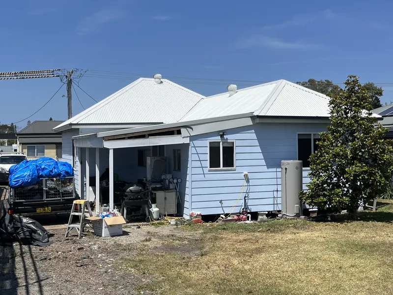 Rear of a weatherboard cottage with its new metal roof