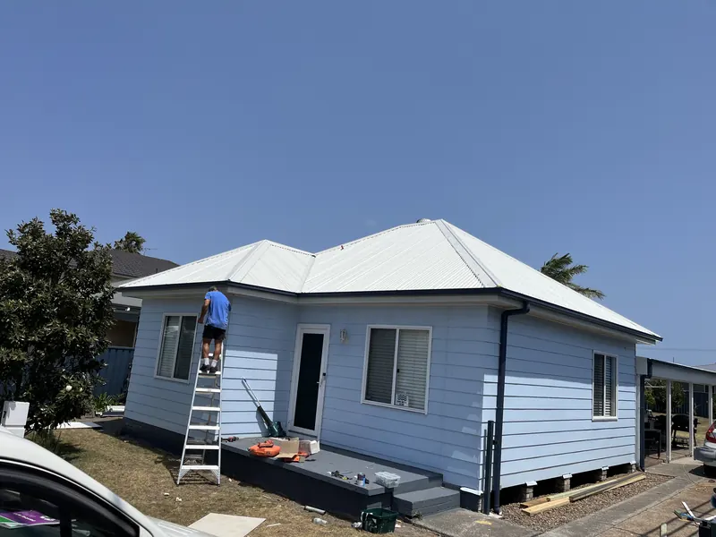Roofer fitting guttering on a weatherboard cottage re-roof