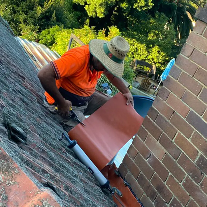Roofer installing flashing against a brick wall