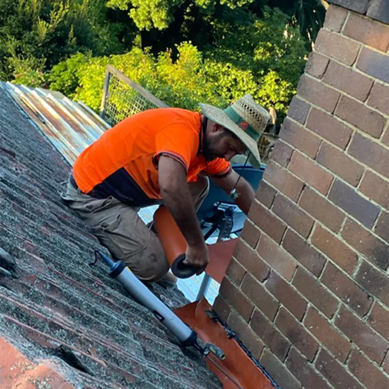 Roofer sealing flashing at a chimney
