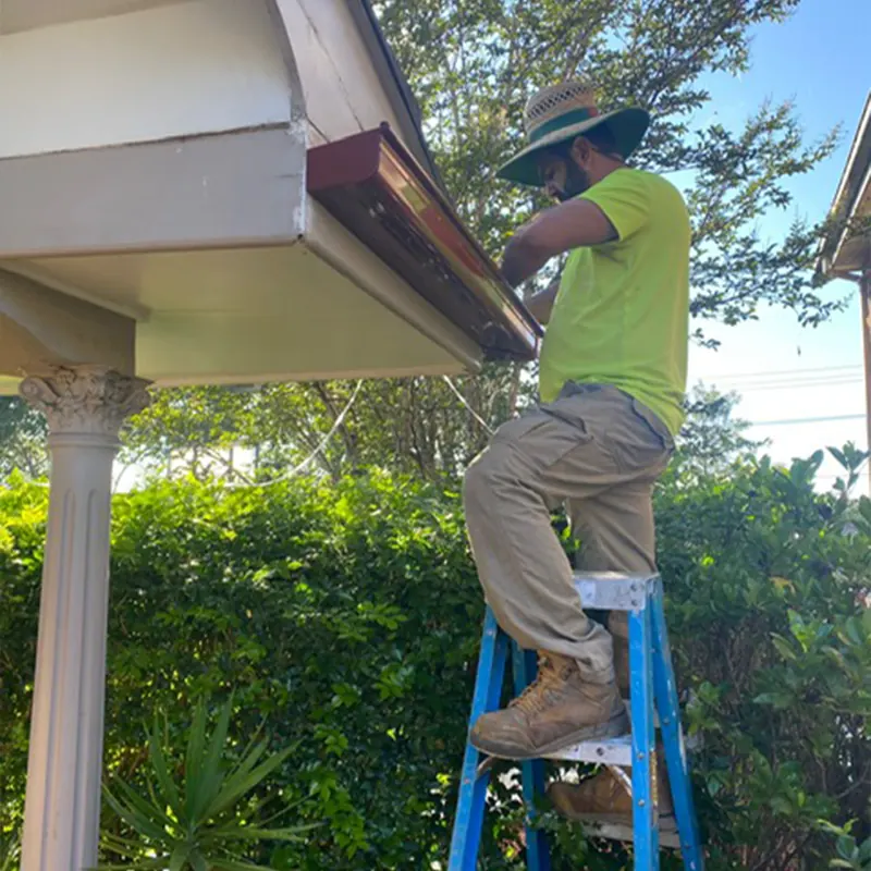 Roofer on a ladder working on a gutter