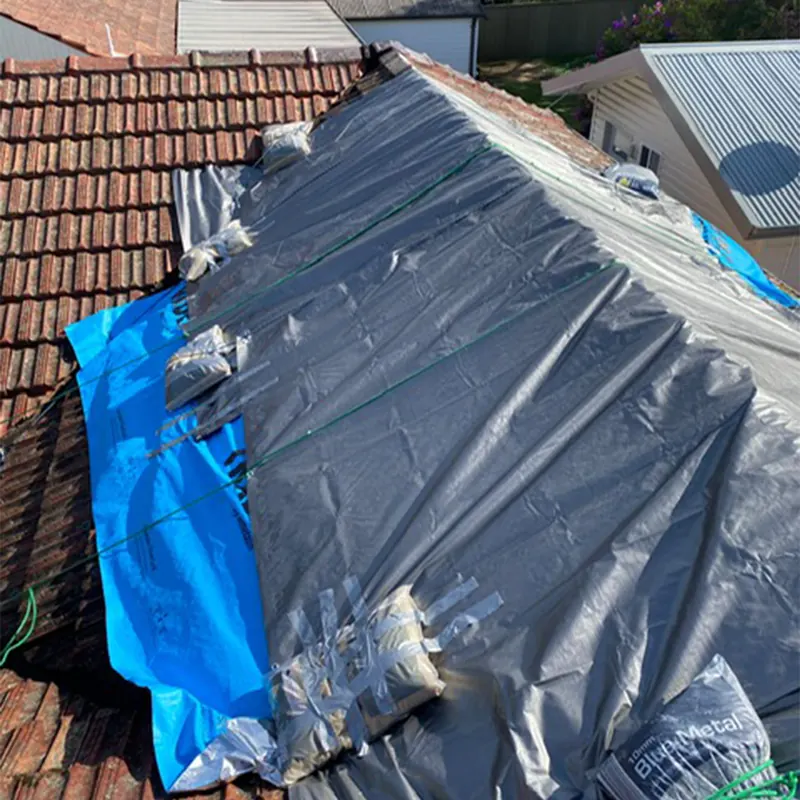 Tarp secured over a damaged tile roof