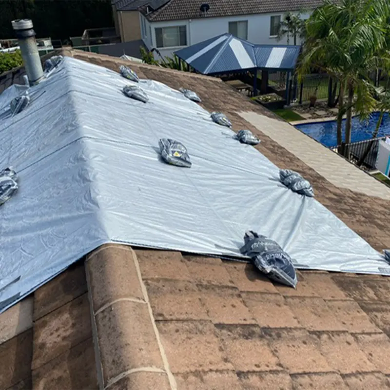 Protective sheeting secured over a tiled roof