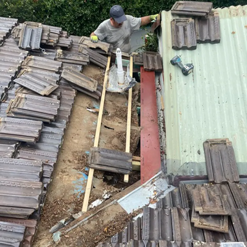Roofer stripping old tiles from a roof